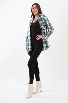 Green plaid flannel shirt worm with a black jumpsuit and white heeled boots