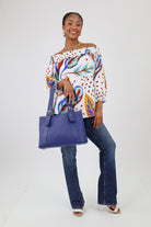 Tropical blouse paired with jeans and a blue tote bag