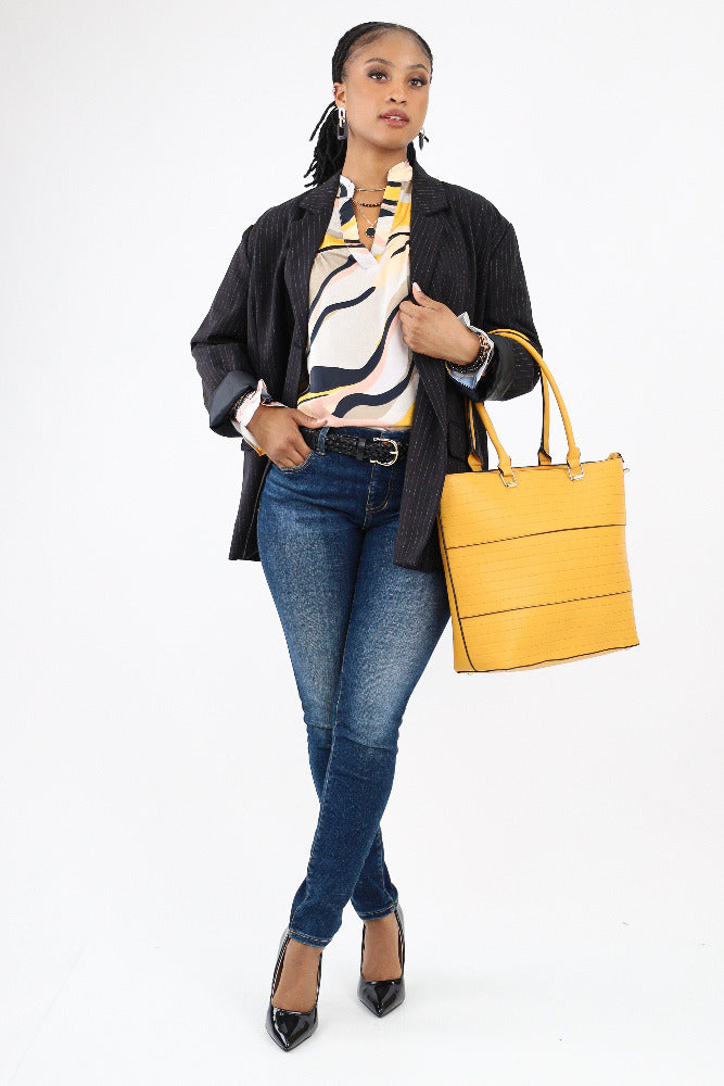 Abstract blouse paired with dark wash jeans, black jackets, and yellow tote bag