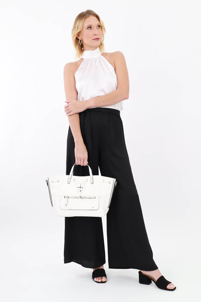 White handbag paired with a satin white halter top, black dress pants, and low heel black slip ons